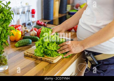 Donna incinta con pompa insulinica che prepara cibo sano nel cucina Foto Stock