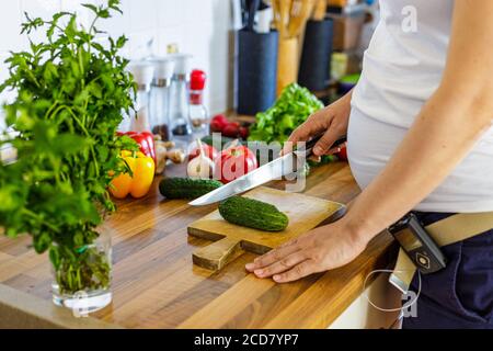 Donna incinta con pompa insulinica che prepara cibo sano nel cucina Foto Stock