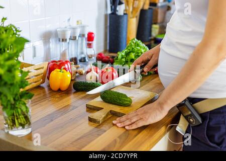 Donna incinta con pompa insulinica che prepara cibo sano nel cucina Foto Stock