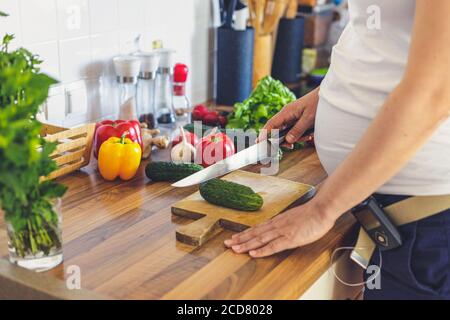 Donna incinta con pompa insulinica che prepara cibo sano nel cucina Foto Stock