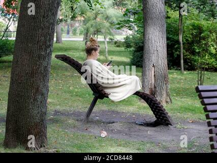 Kiev, Ucraina. 27 Agosto 2020. Una donna usa il suo telefono cellulare mentre si appoggia su una panchina nel parco di Kiev. Credit: Pavlo Gonchar/SOPA Images/ZUMA Wire/Alamy Live News Foto Stock