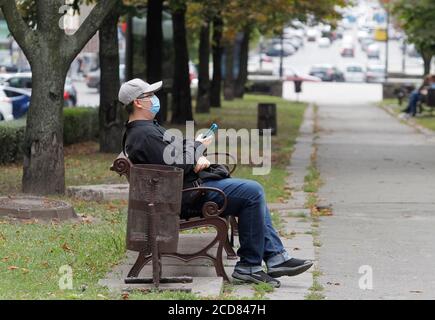 Kiev, Ucraina. 27 Agosto 2020. Un uomo che indossa una maschera facciale come misura preventiva, poggiato su una panchina nel parco di Kiev. Credit: Pavlo Gonchar/SOPA Images/ZUMA Wire/Alamy Live News Foto Stock