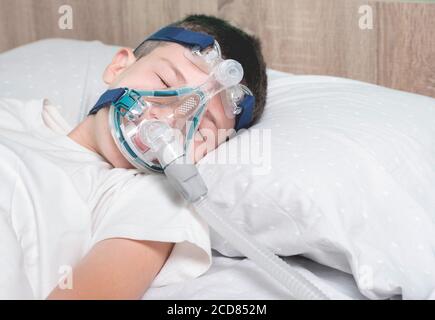Bambino che indossa una maschera nebulizzatrice che dorme sul letto dell'ospedale Foto Stock