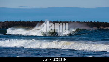 Onde che si infrangono sulla spiaggia rocciosa nella baia di fundy dimostrando il loro immenso potere e le forze della natura. Foto Stock