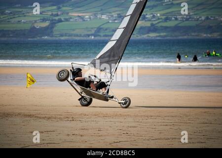 giovane donna che guida blokart a velocità che si ribalta su terreni compatti yacht sulla spiaggia di benone irlanda del nord regno unito Foto Stock