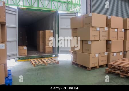 carico spedizione scatole di cartone e merci su pallet di legno a. caricamento del dock dal contenitore Foto Stock