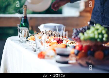 Lungo tavolo coperto da una tovaglia su cui c'è un sacco di cibo, cibo in piatti Foto Stock