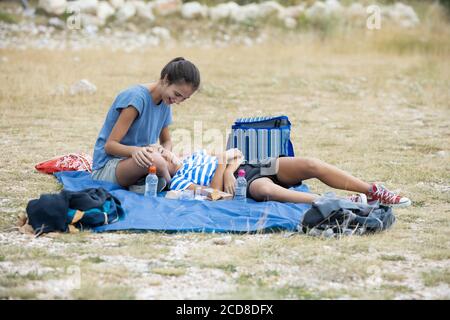 Due sorelle che riposano sulla montagna e la piccola si è addormentato sulle gambe della ragazza più anziana Foto Stock