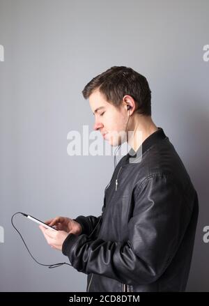 Un giovane che usa lo smartphone per ascoltare la musica indossando le cuffie Foto Stock