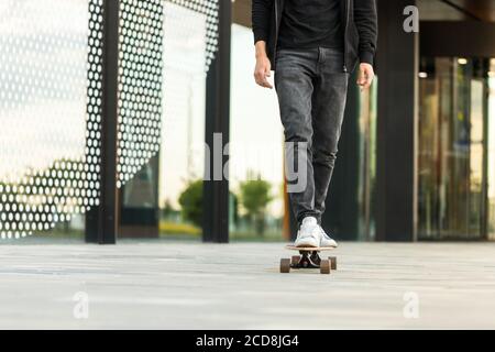 Hipster uomo skateboarder a bordo e pratica longboard in città, all'aperto, immagine ritagliata. Foto Stock