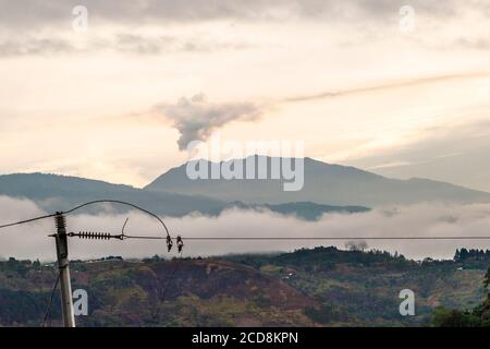 Mattina con linea elettrica di fronte a un fumo Vulcano in Costa Rica Foto Stock