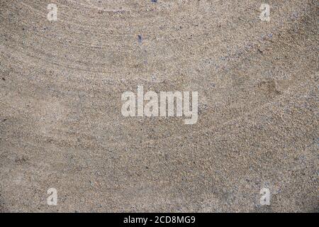 Segni di pennello sulla superficie di sabbia. Creta texture corte. Sabbia granulosa con tacche di livello. Asfalto marrone grigio con polvere. Texture grinta sfondo dettagliato per rustici Foto Stock