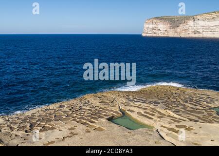 Seascape con scogliere calcaree e saline scolpite nella roccia vicino a Xlendi sull'isola di Gozo, Malta Foto Stock