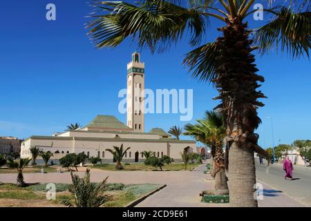 Marocco, Sahara occidentale, Dakhla, donna che indossa abiti tradizionali del Sahara camminando di fronte alla Moschea di Eddarham Foto Stock