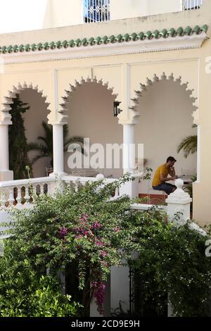 Marocco, Tangeri Tetouan regione, Tangeri, uomo seduto nel patio della legazione americana invaso da bougainvillea Foto Stock