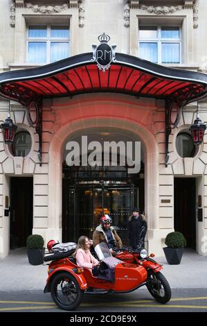 Hotel France, Paris, Royal Monceau, donna che guida in un'auto retrò di fronte alla facciata dell'hotel sorvegliata da due camerieri Foto Stock