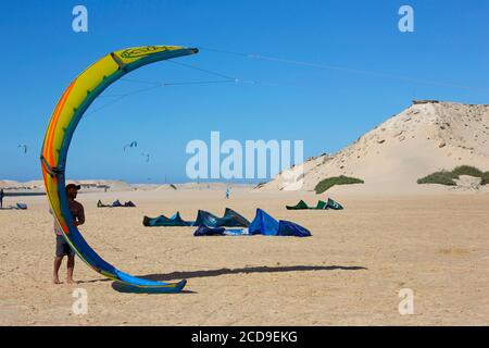 Marocco, Sahara occidentale, Dakhla, kitesurfer che tiene la sua vela sulla spiaggia di Dakhla attitudine kitesurf accampamento Foto Stock