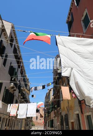 Vestiti appesi ad asciugare e la bandiera d'Italia nella città italiana Foto Stock