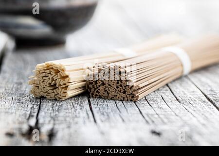 Noodle di soba e udon non cotti. Noodle tradizionali giapponesi su tavolo di legno. Foto Stock