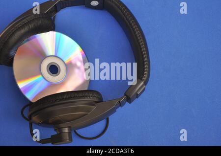 Compact disc e cuffie su sfondo blu con vista dall'alto Foto Stock