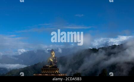 Una statua enorme di Buddha Signore in una mattina soleggiata Nel Parco del Buddha con la cima della neve di Kanchenjunga sullo sfondo A Sikkim in India Foto Stock