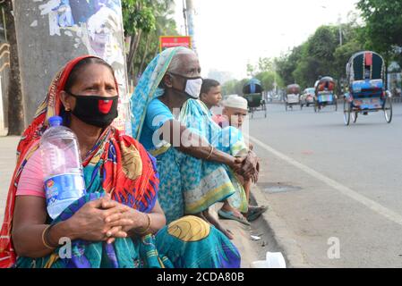 I poveri del Bangladesh attendono aiuti dalla parte del paese strada durante un blocco imposto dal governo come misura preventiva contro Il COVID-19 coronav Foto Stock