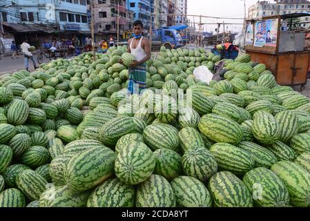 Il fornitore di angurie del Bangladesh attende il cliente in un mercato della cucina durante il governo ha imposto lo spegnimento come misura preventiva contro COVID-19 Foto Stock