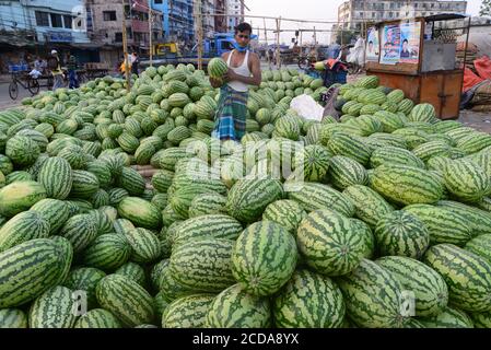 Il fornitore di angurie del Bangladesh attende il cliente in un mercato della cucina durante il governo ha imposto lo spegnimento come misura preventiva contro COVID-19 Foto Stock