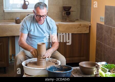 Concetto di ceramica. Ceramista professionista che lavora con creta al tavolo di lancio in officina, studio. Foto Stock