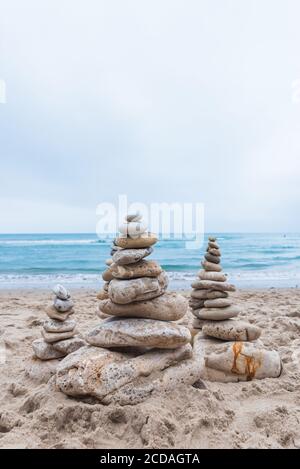 Colpo verticale di ciottoli impilati l'uno sull'altro in una equilibrio in spiaggia Foto Stock