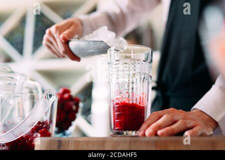 Il barista prepara un cocktail di frutti di bosco sulla terrazza del ristorante. Foto Stock