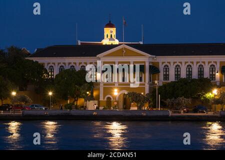 La parte anteriore del Palazzo del Governatore a Fort Amsterdam con la torre illuminata della Fort Church dietro. Situato nel quartiere di Lunda di Willemstad, il capi Foto Stock