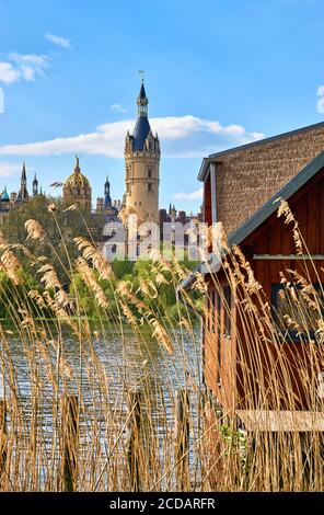 Canne e boathouse in legno sul lago di Schwerin con il castello sullo sfondo. Foto Stock