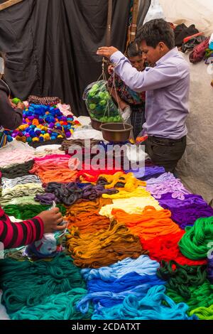 Un uomo pesa filo per tessitura per la vendita nel mercato all'aperto a Chichicastenango, Guatemala. Foto Stock