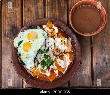 I peperoncini con uova fritte e una ciotola di atole champurrado è una tipica colazione Oaxacan. Le tortillas di mais vengono tagliate in quarti e leggermente fritte. T Foto Stock