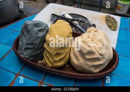 Impasto di tortilla composto da masa di mais blu, giallo e bianco. Dietro c'è una piccola torciglia metallica. Foto Stock