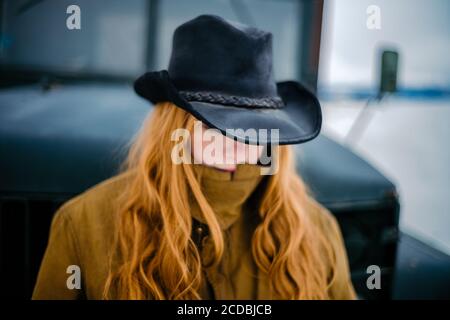 Donna con testa in giù indossare cappello, patta nascondiglio viso, rossetto rosso, stile cowboy Foto Stock