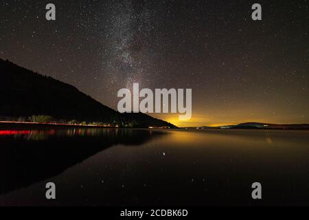 Lago di Bassenthwaite nel distretto dei laghi con la Via Lattea E luci per auto che si tirano dalla A66 sul lago Foto Stock