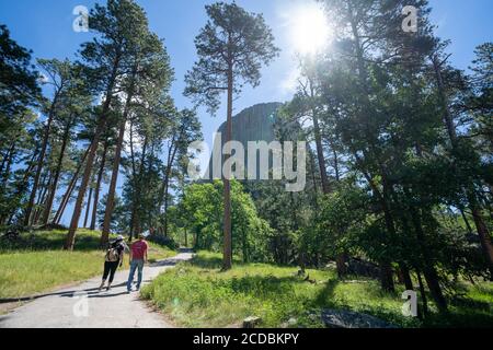 Wyoming, USA - 23 giugno 2020: Due escursionisti camminano verso il monumento nazionale della Devils Tower al mattino Foto Stock