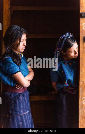 Due donne Maya peer fuori la porta di Sant Antonio da Padova la chiesa di San Antonio Palopó, Guatemala, indossando abiti tipici del loro villaggio, inclu Foto Stock