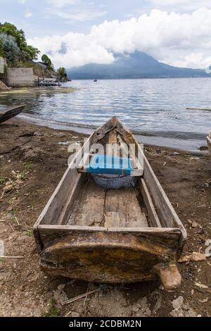 Un cayuco o barca da pesca sulla riva del lago Atitilan a San Antonio Palopo, Guatemala con una barca da pesca sul lago Atitlan e il San Pedro Volcan Foto Stock