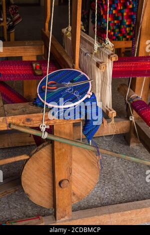 Un cerchio ricamato con tessuto intrecciato si trova su un tradizionale telaio di legno piede-treadle a San Antonio Palopo, Guatemala. Il tessuto era tessuto su una schiena Foto Stock