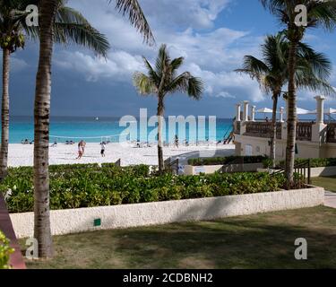 I turisti giocano a pallavolo sulla spiaggia di sabbia bianca del Mar dei Caraibi fuori da un hotel di lusso. Cancun, Quintana Roo, Penisola dello Yucatan, Messico. Foto Stock