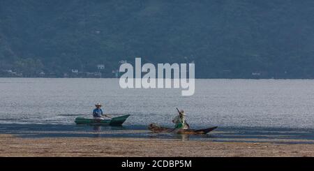 Due pescatori maya a cayucos pescano lungo un letto di muschio sul lago Atitlan, Guatemala. Foto Stock