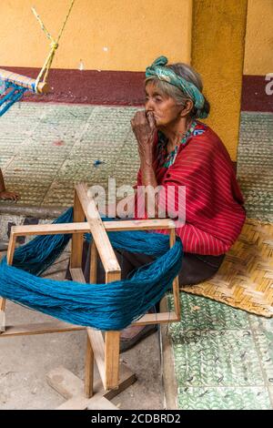 Una donna maya Cakchiquel più anziana in abito tradizionale avvolge il filo su un telaio per prepararsi a tessere su un telaio posteriore a Santa Cruz la Laguna, Guatemala. Foto Stock