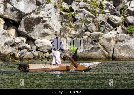 Un uomo Maya in abito tradizionale pagaia il suo cayuco sul lago Atitlan vicino Santiago Atitlan, Guatemala. Foto Stock