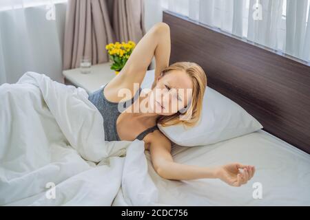 Turbata giovane donna sdraiata a letto al mattino sente dolore al collo dopo il sonno notturno, risvegliata con dolore improvviso o rigidità, postura errata Foto Stock