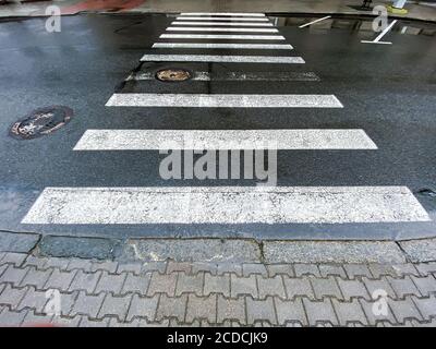 passerella pedonale con segnaletica stradale sull'asfalto umido scuro strada Foto Stock