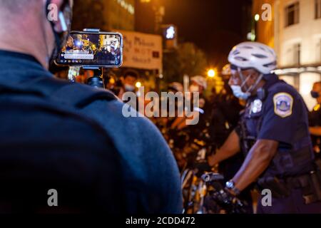 Washington, DC, Stati Uniti. 27 Agosto 2020. Nella foto: Un uomo trasmette un confronto tra un protessore e gli ufficiali della polizia metropolitana (DC) vivono sui social media durante le proteste anti-razzismo a Black Lives Matter Plaza la notte prima della marcia a Washington. Credit: Allison C Bailey/Alamy Credit: Alison Bailey/Alamy Live News Foto Stock