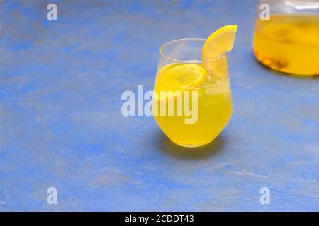 Zenzero turmerico limonata in una tazza di vetro su sfondo blu con spazio per la copia Foto Stock